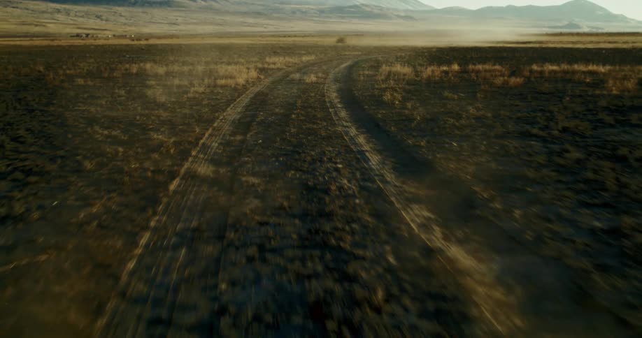 Tire tracks left by a car as it moves across a badland at midday