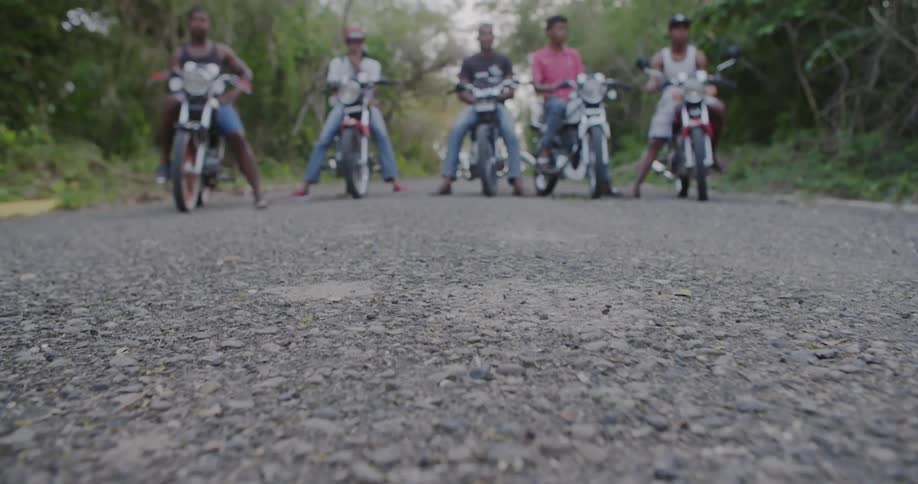 Men sit on motorcycles on a narrow forest road