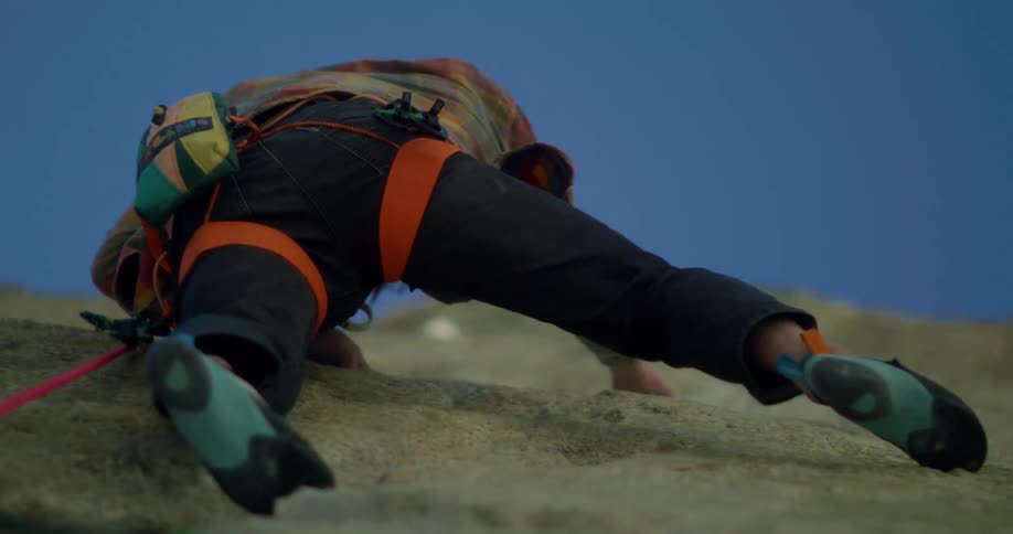 A mountain climber ascends a rock at midday