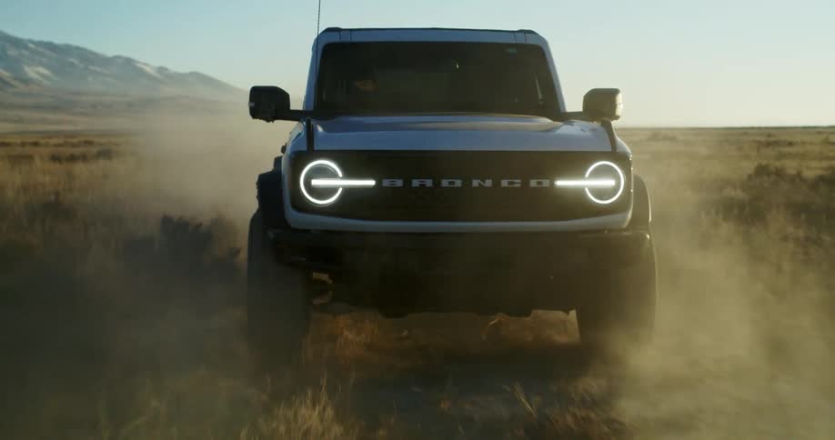 White ford kicking up dust on a dirt road in the countryside