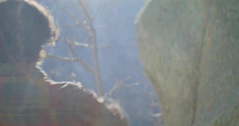 A hiker takes his coat off and hangs it on a tree