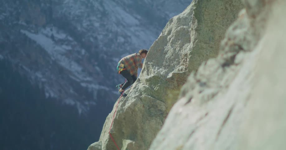 A man climbing a rocky mountain at midday