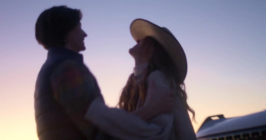 The video shows two people standing in front of a white ford bronco a man and a woman the man lifts a cowboy hat from the womans head and places it on his own head