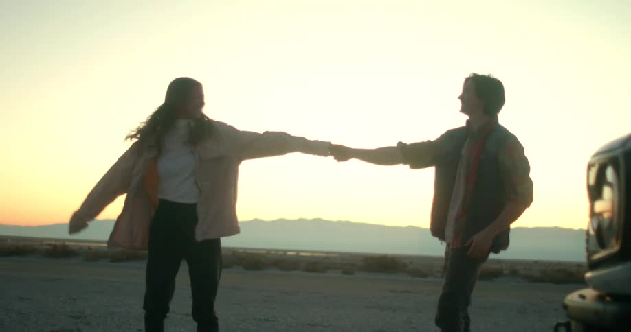 Couple kissing while leaning against a white ford bronco at sunset