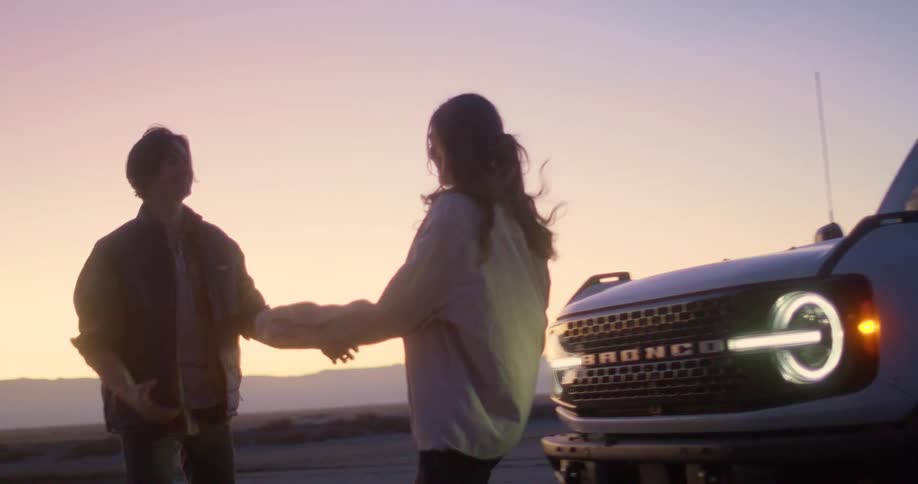 A man getting out of an suv wearing a cowboy hat and then hugging and spinning with a woman and they are happy