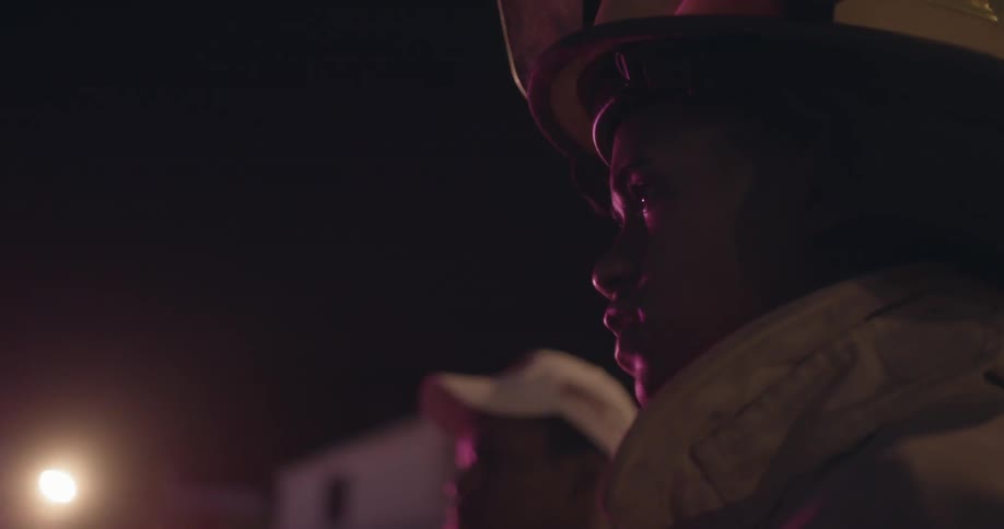 Flashing lights shine on a firefighter's face at night