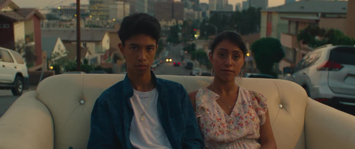 Young couple sitting on a couch outdoors with a view of the city