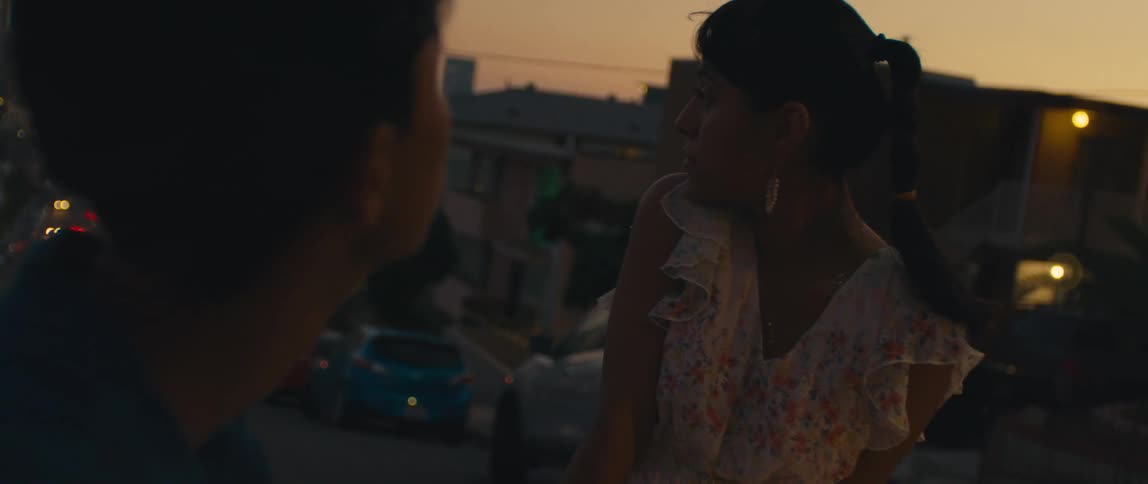 Two young people watch the street at dusk in an urban area