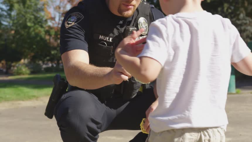 Police officer gives a toy badge to a child in the park