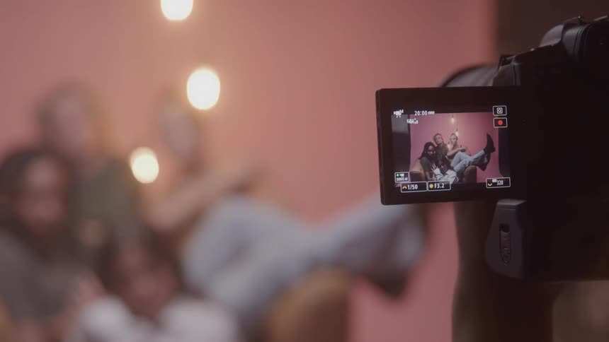 Person with a professional camera filming a group of people in a studio