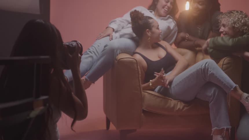 A group of models poses on a couch in a studio photoshoot