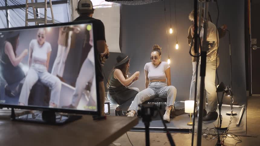 A woman is being prepped with makeup during a fashion photoshoot