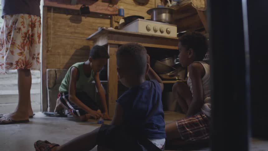 Children play on a kitchen floor as a woman walks around them