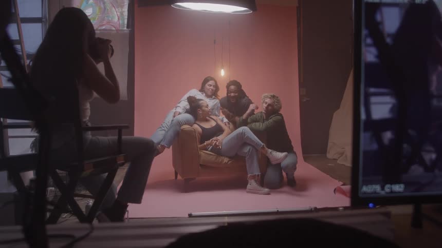 A group of models pose together on a couch during a photoshoot