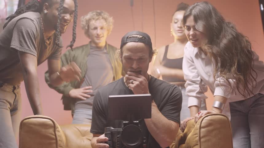 People surround a man holding a video camera in a studio