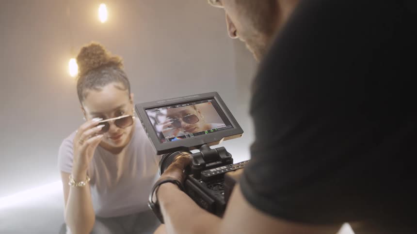 Woman in sunglasses being filmed up close by a cameraman