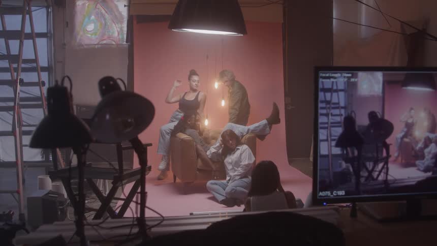 Models posing in a studio photoshoot with lights and backdrop