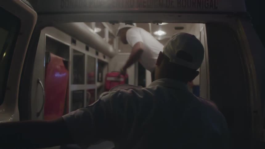 Ambulance workers are working inside and outside of an ambulance