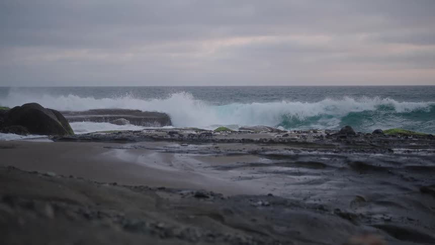 A wave breaking on the rocky coast and making a splash upwards