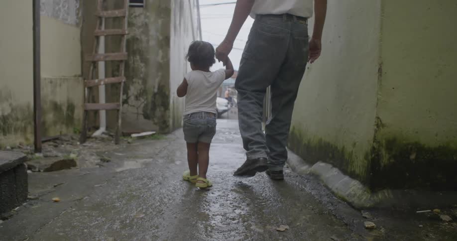 A man walks through an alleyway holding hands with a girl