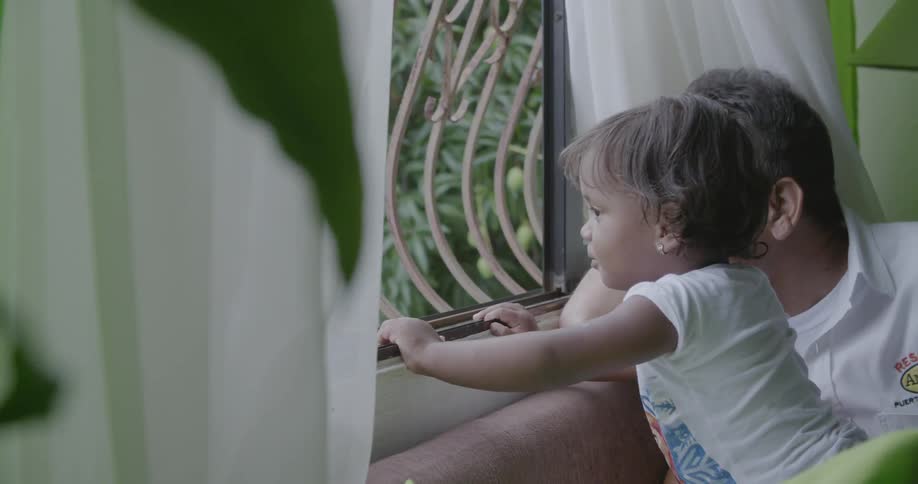 A man holds a child to look out the window