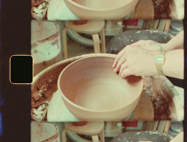 A person shapes clay on a pottery wheel in a ceramics studio
