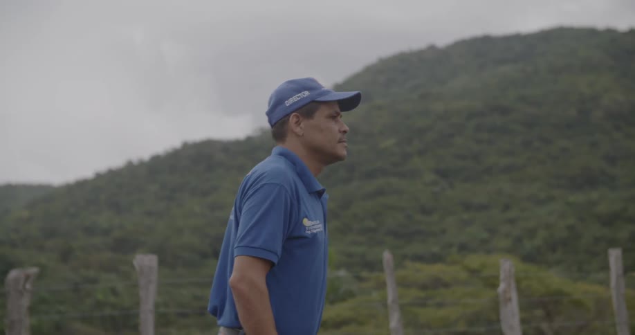 A man walks outdoors in a rural area on a cloudy day