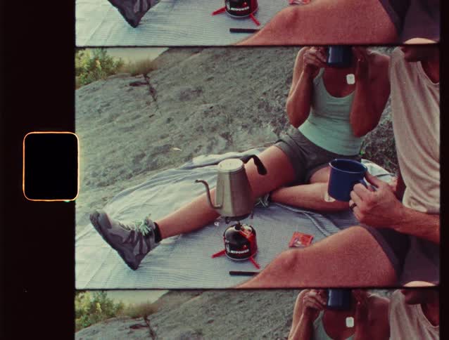 Couple sit on a blanket with coffee and camping gear