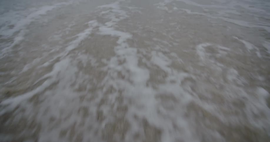 A wave and foam trails off as it recedes from the beach