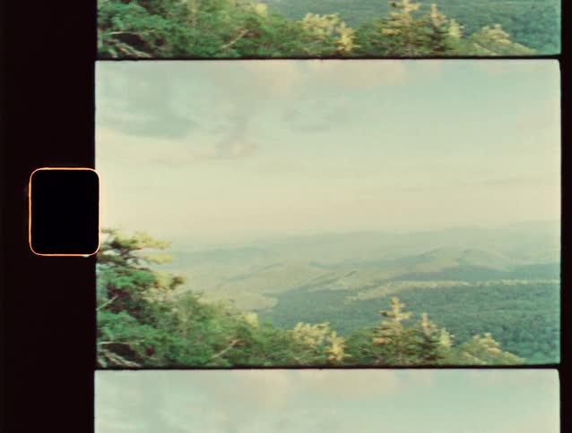 A hazy mountain landscape with trees in the foreground