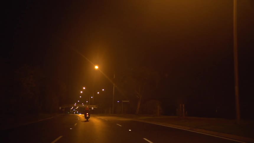 Motorcycle riding down a street at night