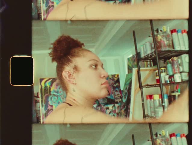Tattooed woman painting a colorful canvas in an art studio