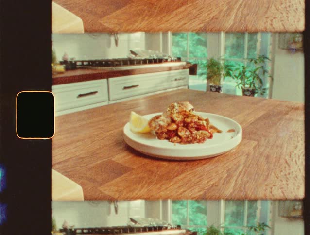Plate of cooked shrimp is served with lemon slices in a kitchen