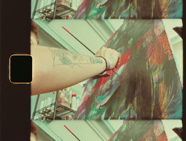 Tattooed arm paints a colorful canvas with a red brush