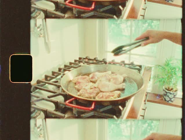 Hand uses tongs to grill pieces of meat in a frying pan on the stove