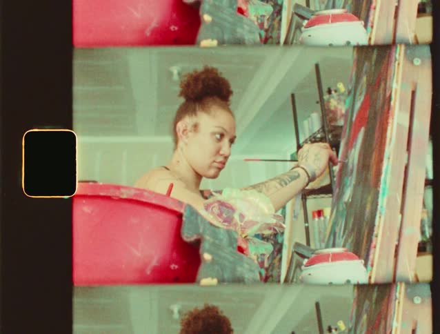 A woman paints on a large canvas in a studio
