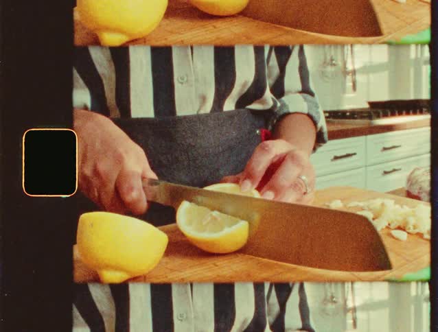 A woman in the kitchen cuts a lemon on a cutting board with a knife
