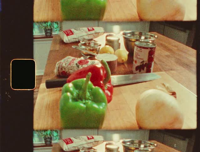 Several ingredients including peppers and onions are atop a kitchen counter