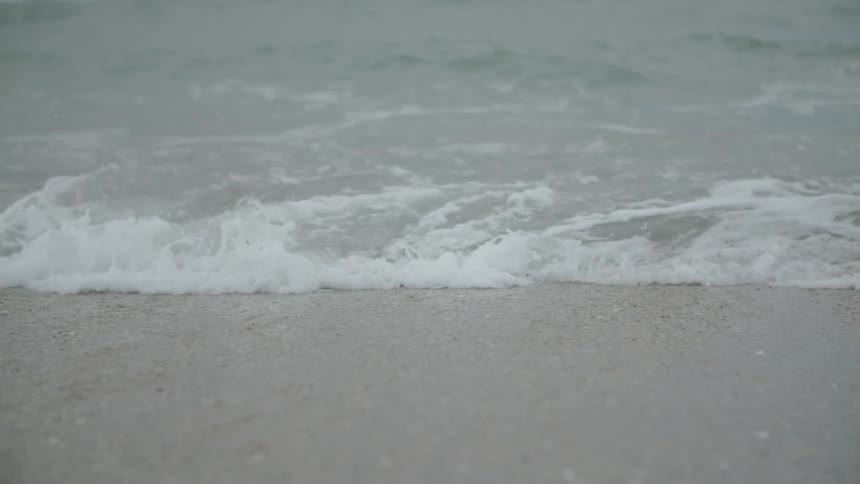 Waves crash against the shore of the beach