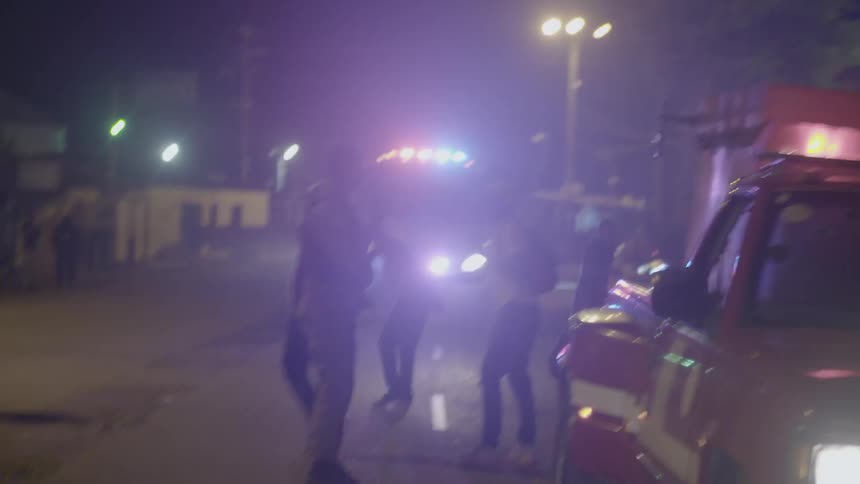 A tanker truck with flashing lights navigates a busy street
