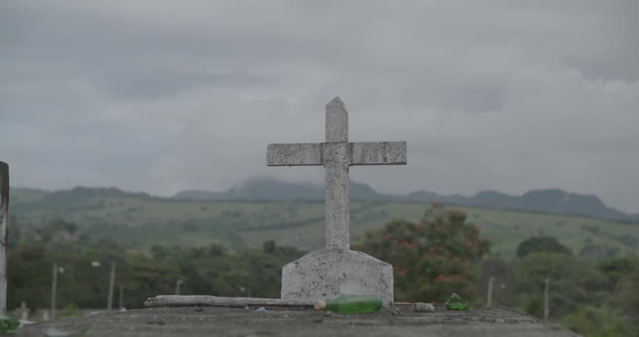 A cross stands with trees and clouds in the distance
