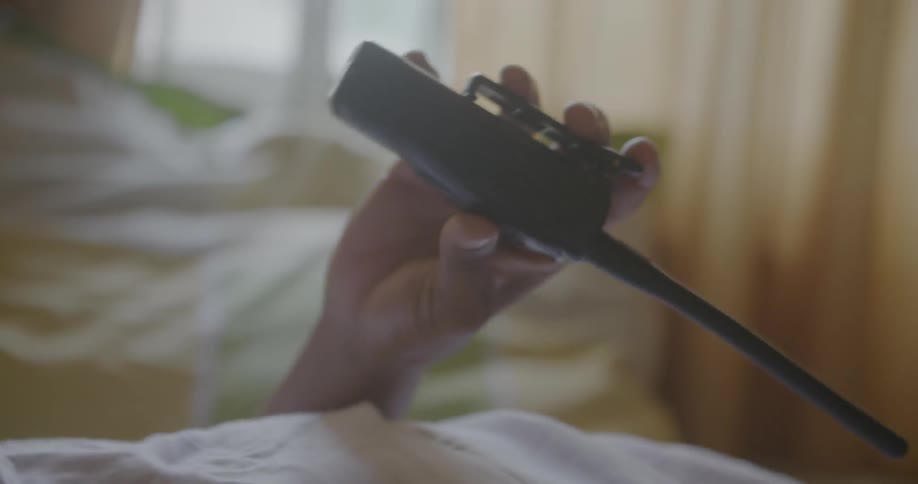 A man holds a walkie talkie as he lays in bed