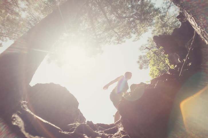 A hiker ascending a sundrenched rocky trail captured from a low angle