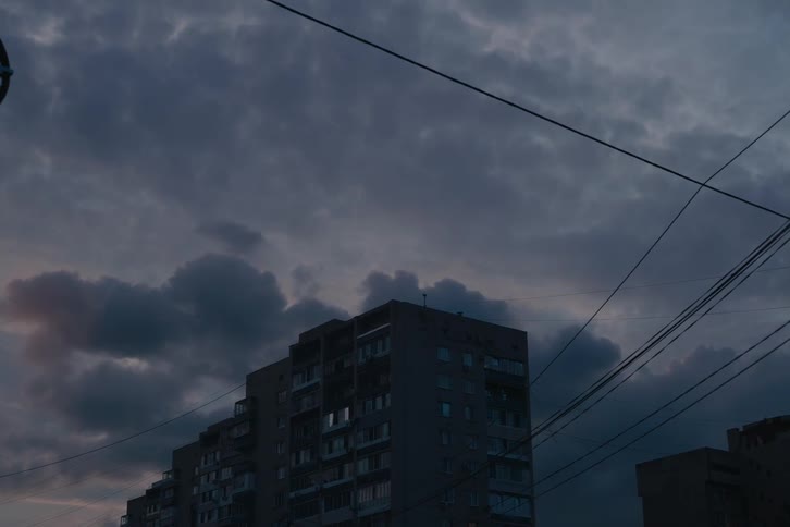 A dark apartment building under a cloudy evening sky