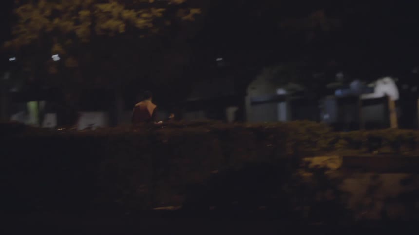 A man rides down the road on a motorcycle at night