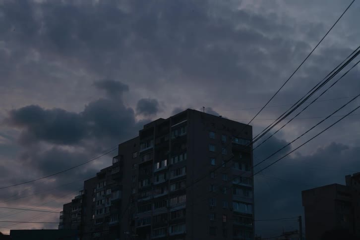 An apartment building stands dark beneath a cloudy evening sky