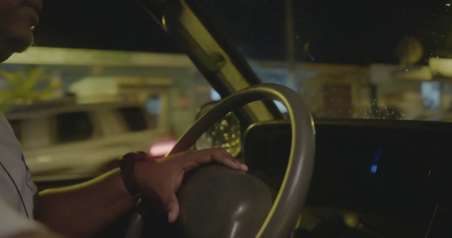 A person drives a vehicle down the road at night