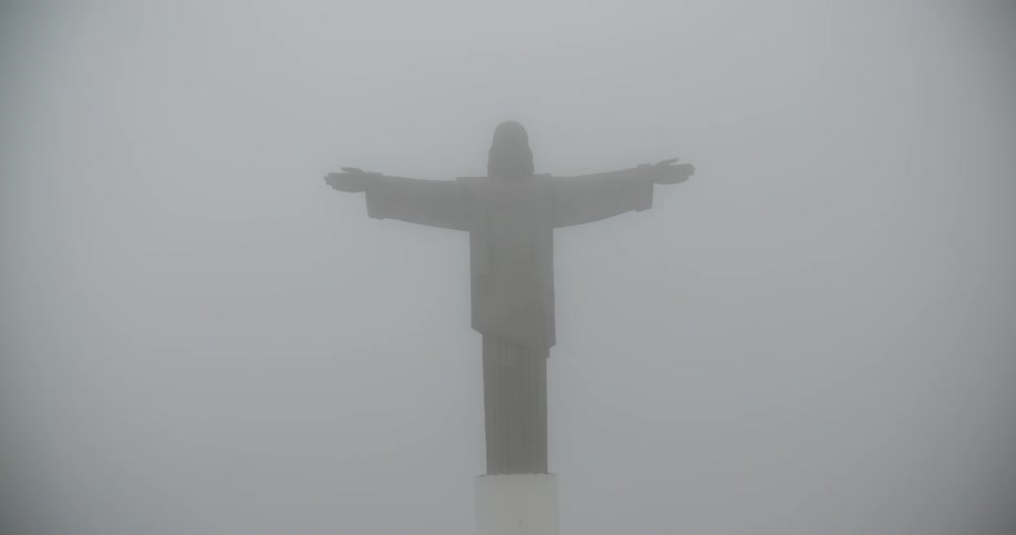 A tall statue of a man is in the fog ahead