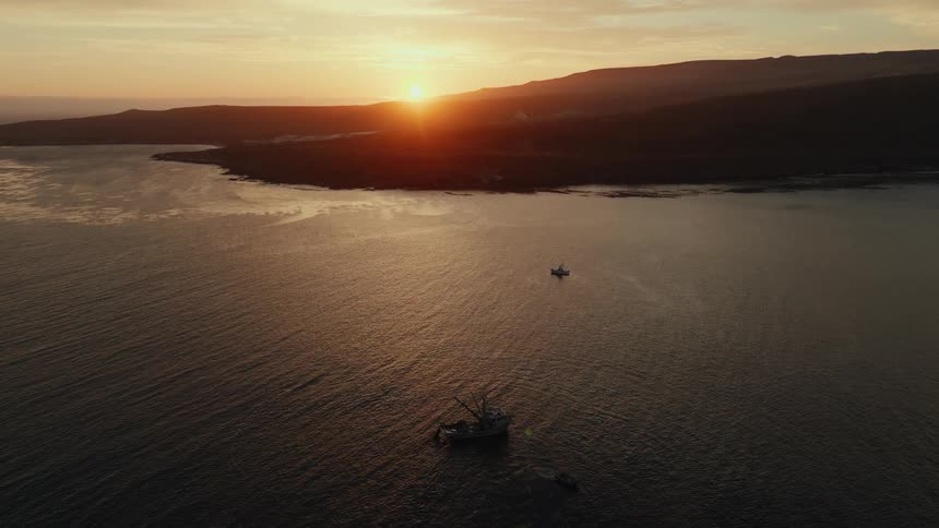 Boats sailing on calm sea during sunset near the coast