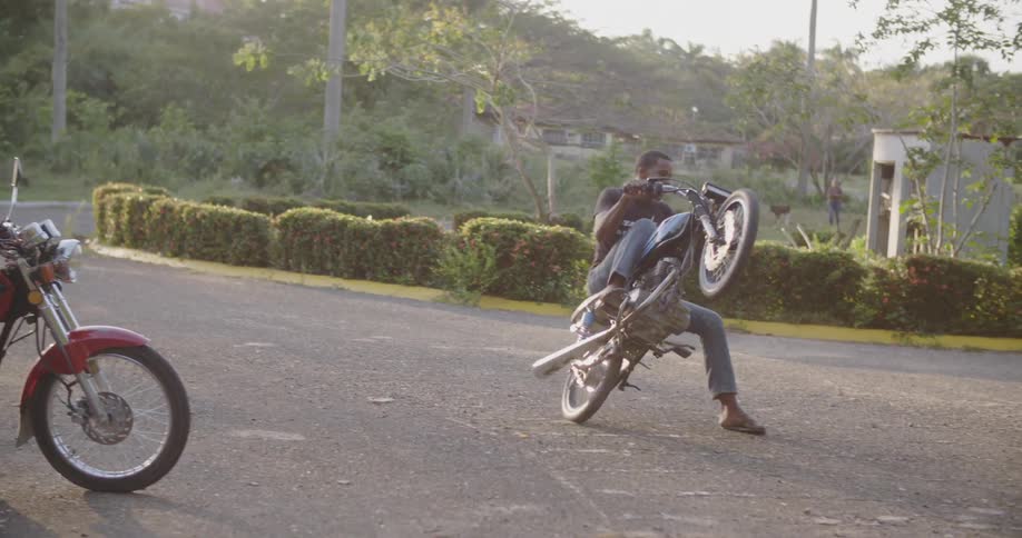 A man does donut wheelies and then falls off his motorcycle